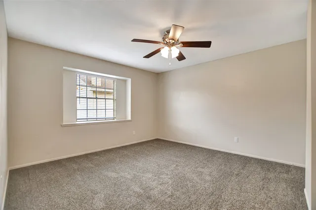 an empty room with a window and a fan