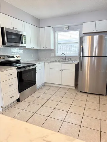 a kitchen with granite countertop a refrigerator and a stove top oven