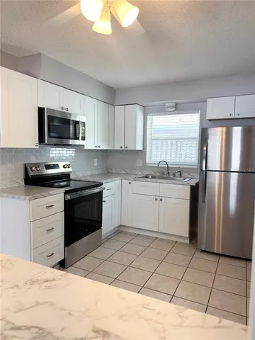 a kitchen with a sink a stove a refrigerator a microwave and cabinets