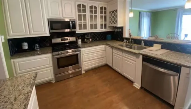 a kitchen with stainless steel appliances granite countertop a stove a sink and a microwave