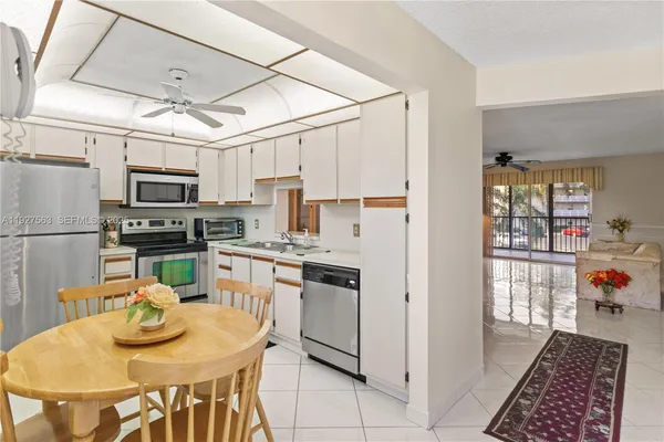 a kitchen with stainless steel appliances granite countertop a stove a refrigerator a sink dishwasher a dining table and chairs with wooden floor