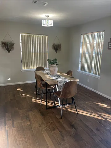 a dining room with wooden floor a chandelier a wooden table and chairs