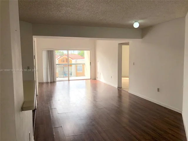 an empty room with wooden floor and windows with curtains