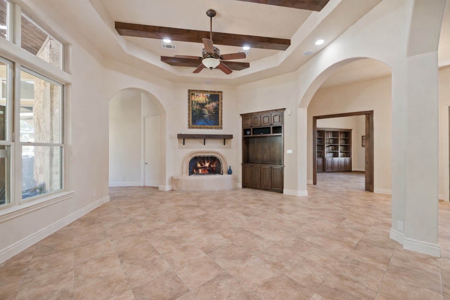 109 Ranchers Club Lane Driftwood, TX 78619 - Photo 6 of 19 Open concept living room with arched walkways, a lit fireplace, beam ceiling, recessed lighting, and a ceiling fan