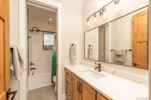 a bathroom with a granite countertop sink mirror and a bathtub