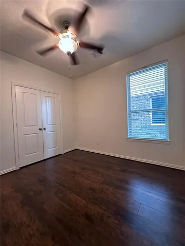 an empty room with wooden floor chandelier fan and windows