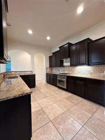 a large kitchen with granite countertop a stove a sink and a microwave