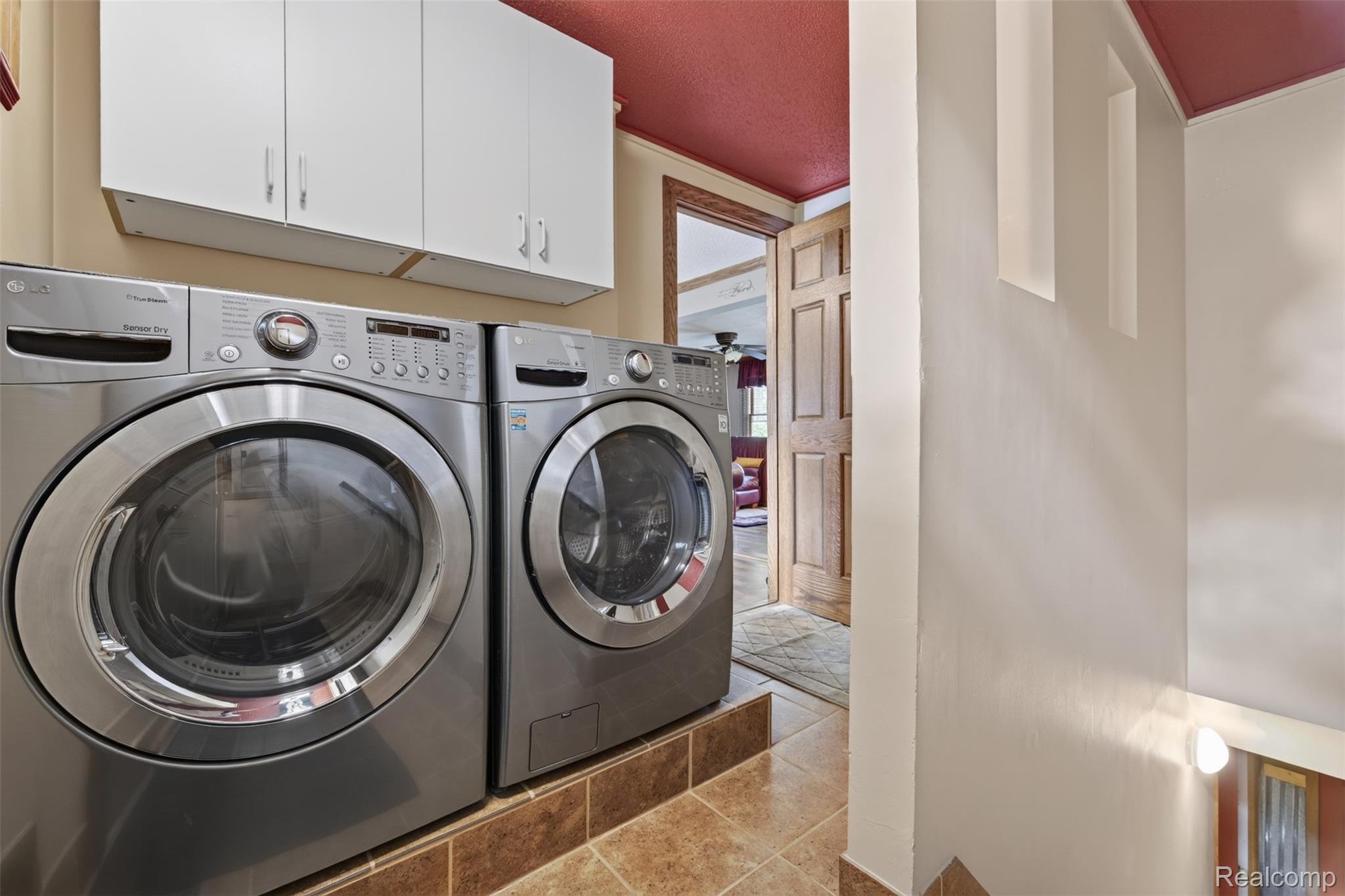 5977 Anglers Road Ortonville, MI 48462 - Photo 14 of 63 Dedicated laundry area featuring front-loading appliances, white upper cabinetry, and tiled flooring