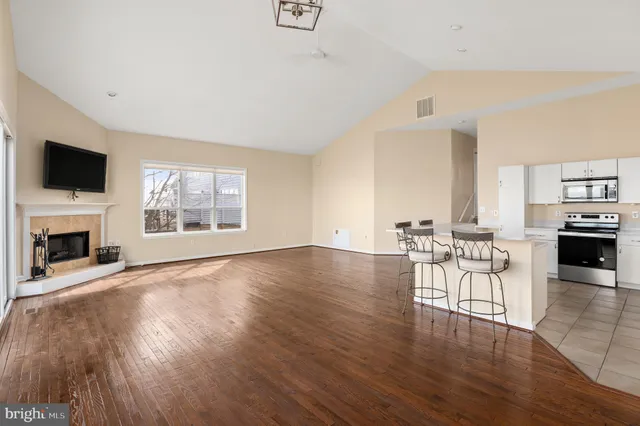 a view of a livingroom with furniture a fireplace wooden floor and windows