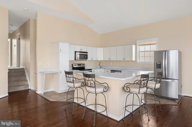 a kitchen with stainless steel appliances a table chairs refrigerator and wooden floors