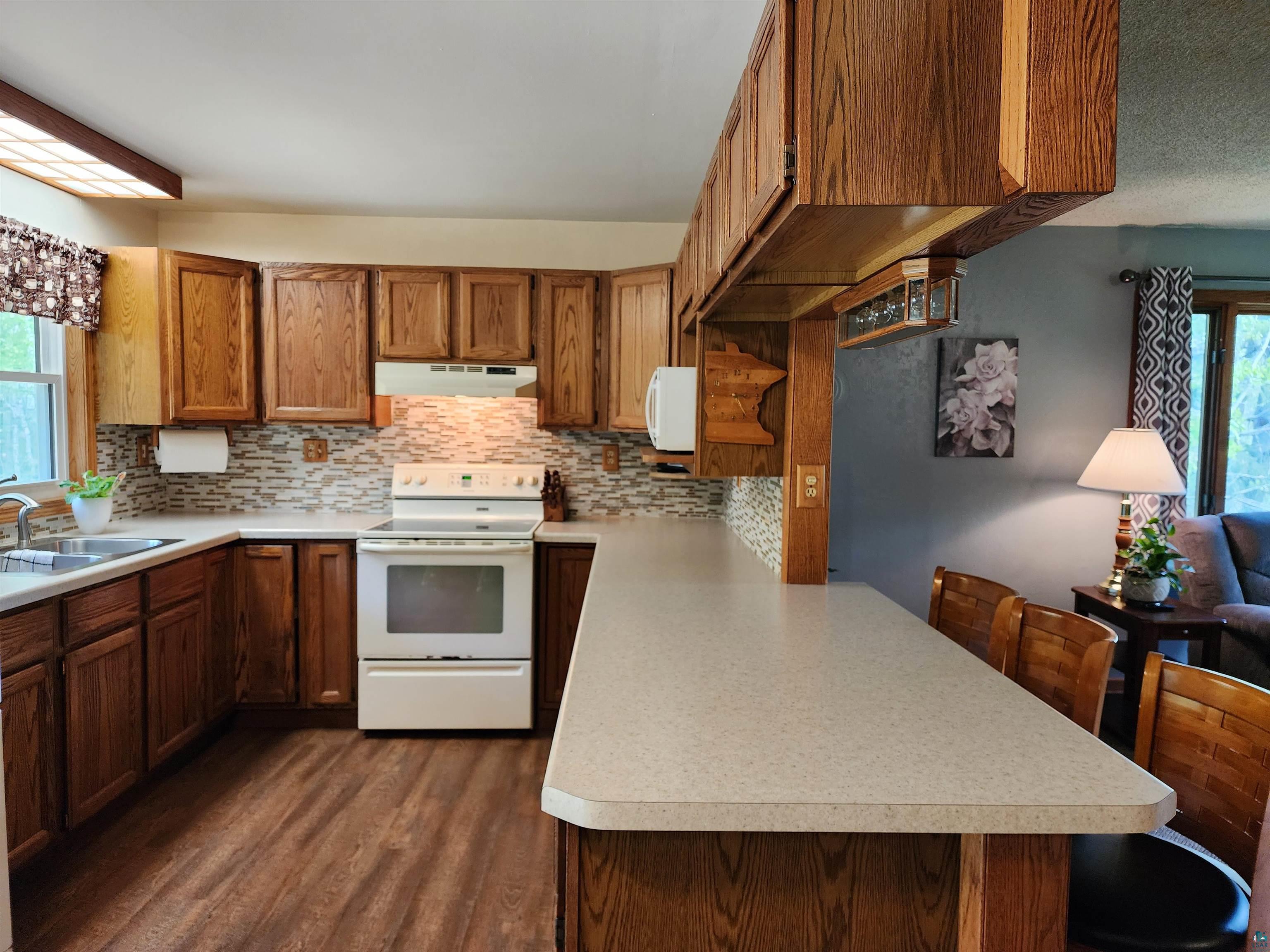 4179 Willard Road Rice Lake, MN 55803 - Photo 4 of 39 Kitchen featuring dark hardwood / wood-style floors, a healthy amount of sunlight, white electric range oven, and backsplash