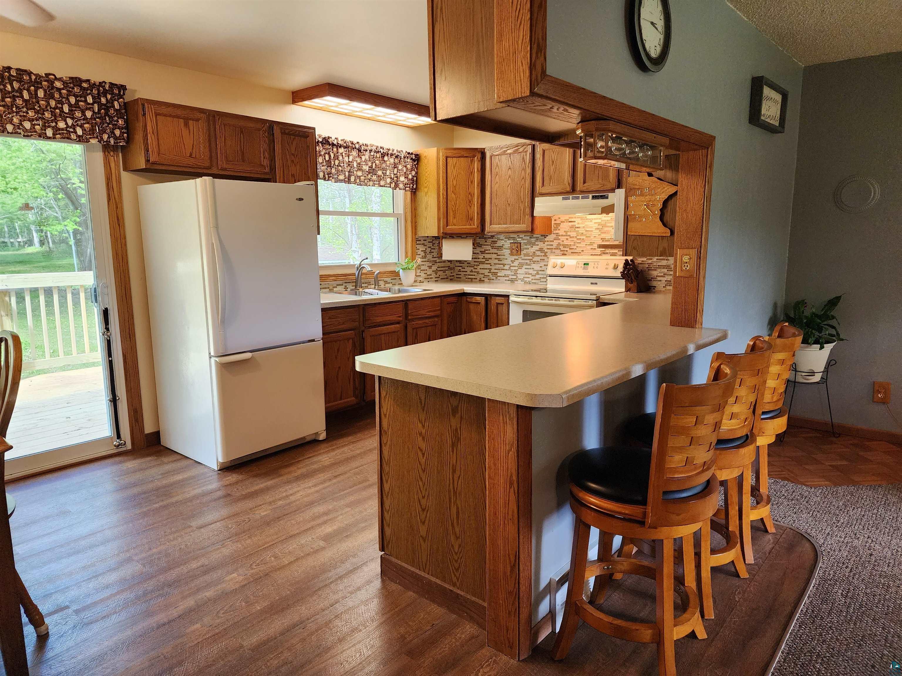 4179 Willard Road Rice Lake, MN 55803 - Photo 7 of 39 Kitchen with white appliances, kitchen peninsula, hardwood / wood-style floors, sink, and tasteful backsplash