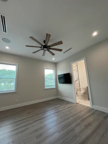an empty room with wooden floor and windows