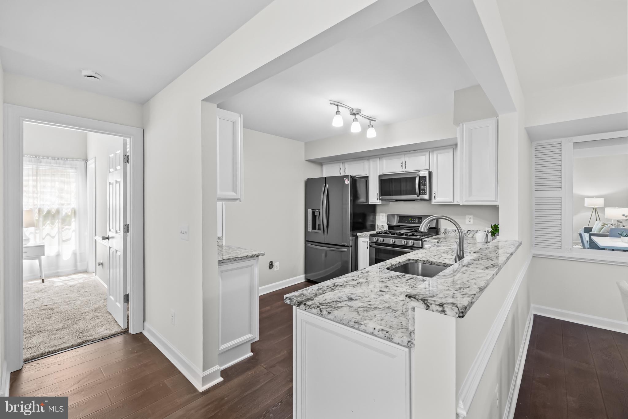 17045 Islip Loop, Unit 303 Dumfries, VA 22026 - Photo 13 of 48 a kitchen with kitchen island granite countertop stainless steel appliances cabinets a sink and a counter top space