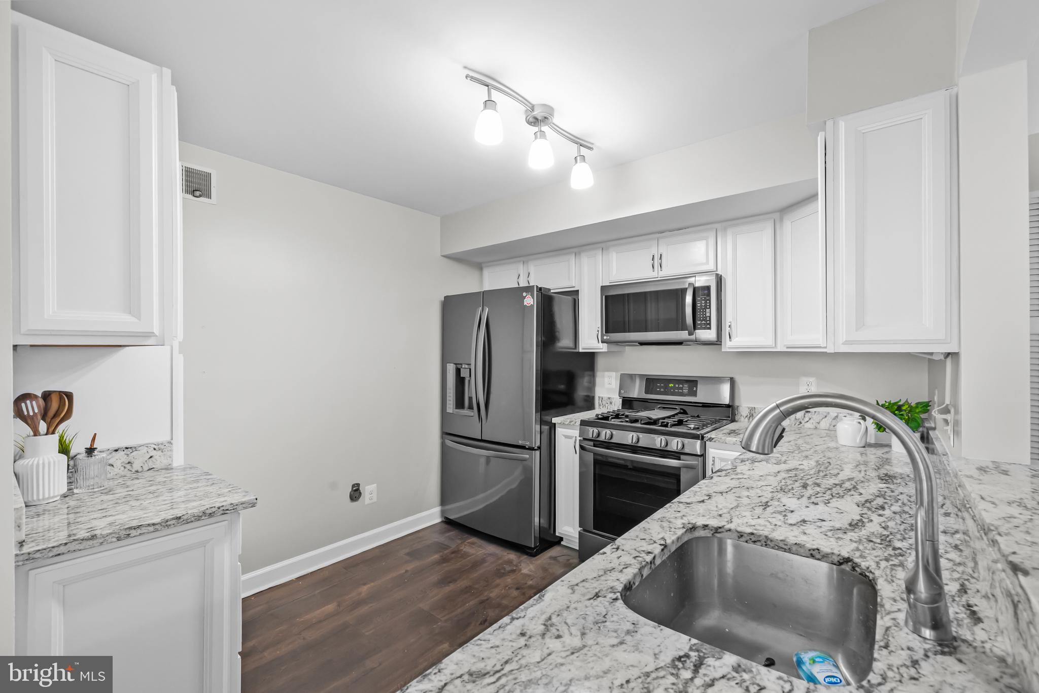 17045 Islip Loop, Unit 303 Dumfries, VA 22026 - Photo 15 of 48 a kitchen with granite countertop a refrigerator sink and microwave