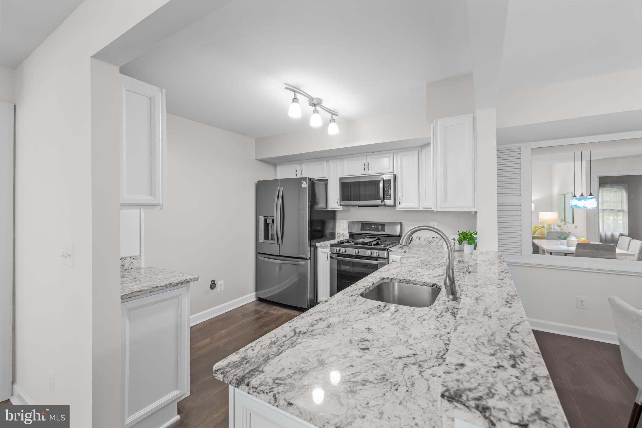 17045 Islip Loop, Unit 303 Dumfries, VA 22026 - Photo 19 of 48 a kitchen with stainless steel appliances kitchen island sink refrigerator and microwave