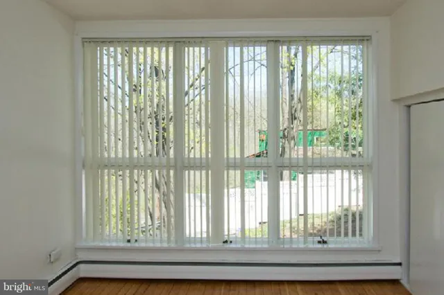 a view of an empty room with hardwood and a window