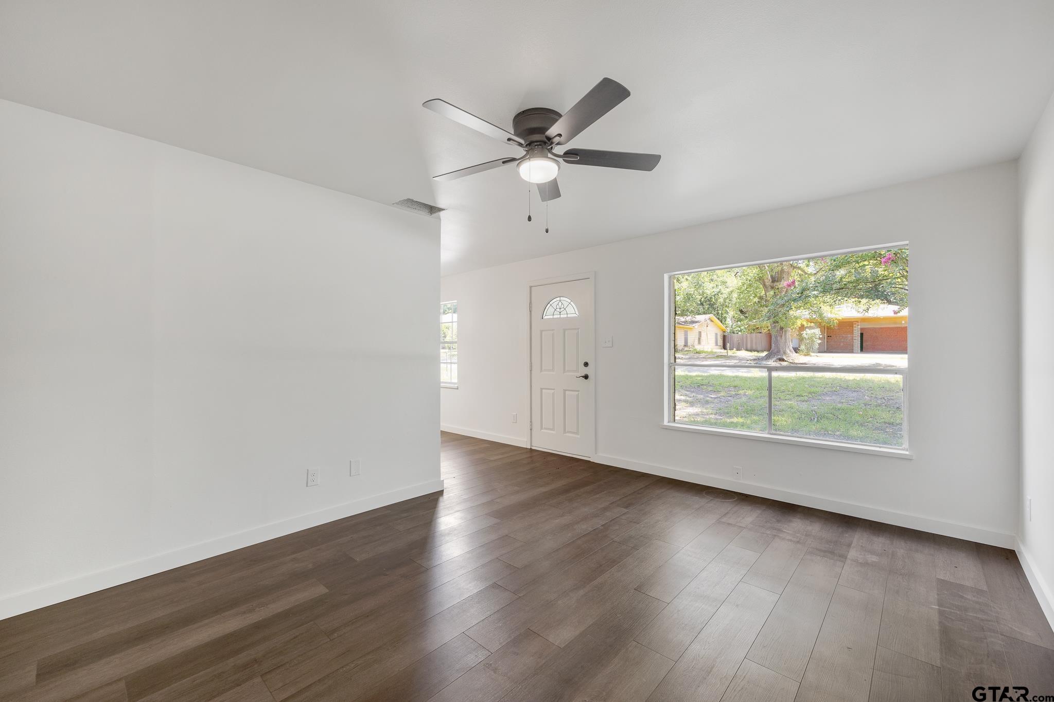 1538 North Hill Road Tyler, TX 75702 - Photo 7 of 29 an empty room with wooden floor fan and windows