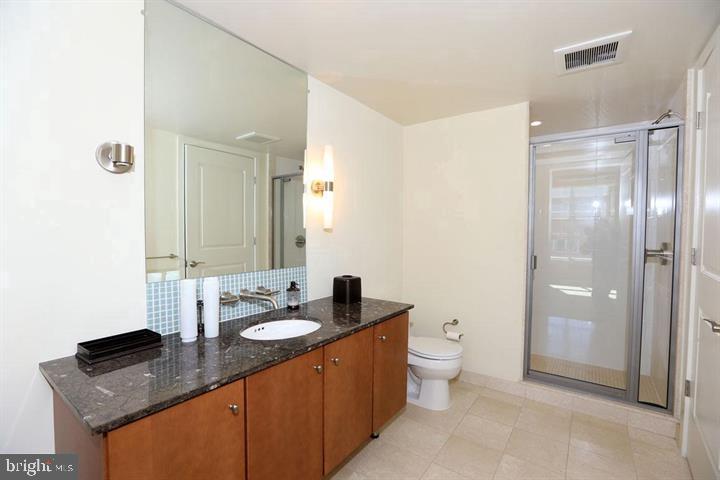 1025 First Street Southeast, Unit 1012 Washington, DC 20003 - Photo 12 of 22 a bathroom with a granite countertop sink a toilet a large mirror and shower
