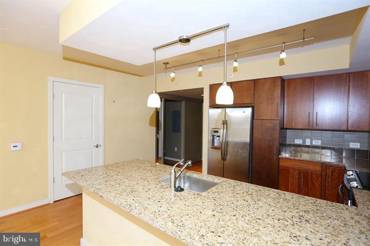 1025 First Street Southeast, Unit 1012 Washington, DC 20003 - Photo 6 of 22 a kitchen with stainless steel appliances kitchen island granite countertop a refrigerator and microwave