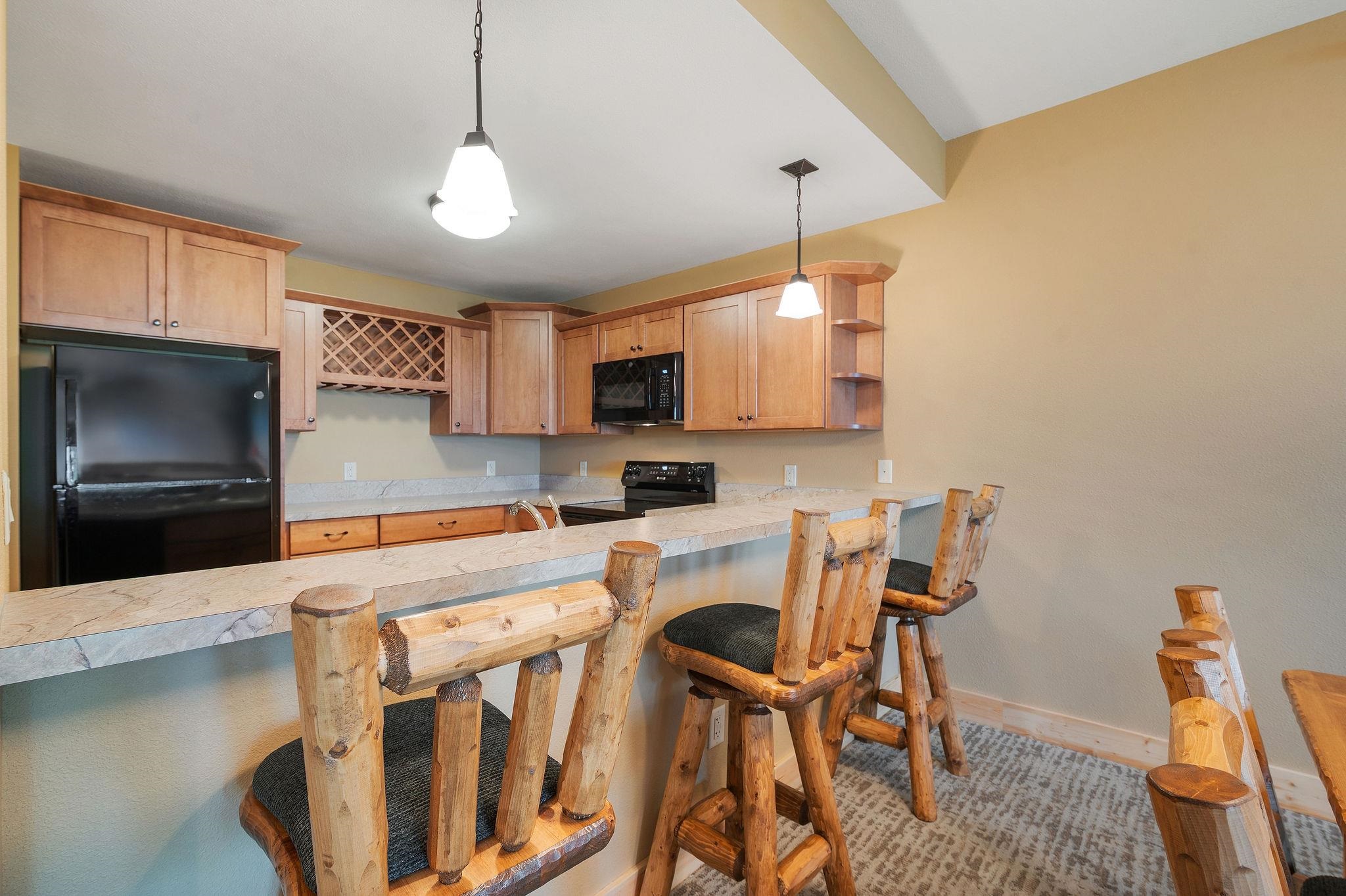 Two Burlington Road, Unit 5102 Two Harbors, MN 55616 - Photo 7 of 30 Kitchen featuring black appliances, light countertops, hanging light fixtures, a peninsula, and a kitchen breakfast bar