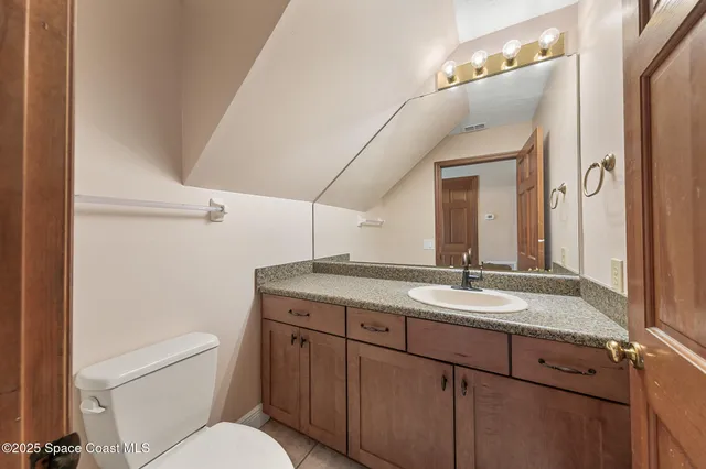 a bathroom with a granite countertop sink a toilet and a mirror