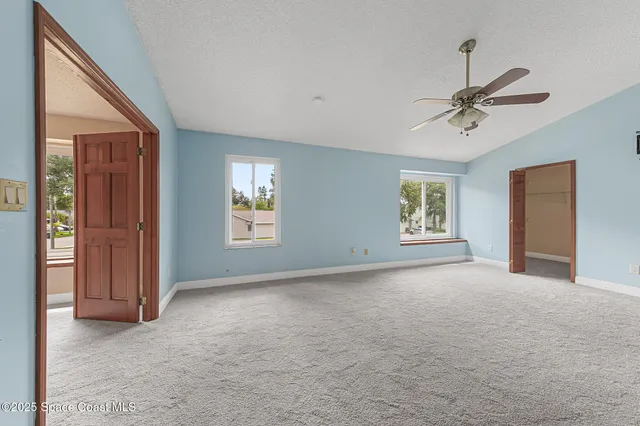 an empty room with windows and fan