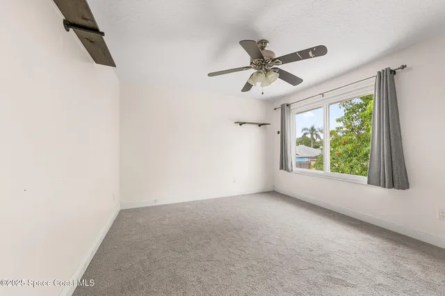 an empty room with windows and fan