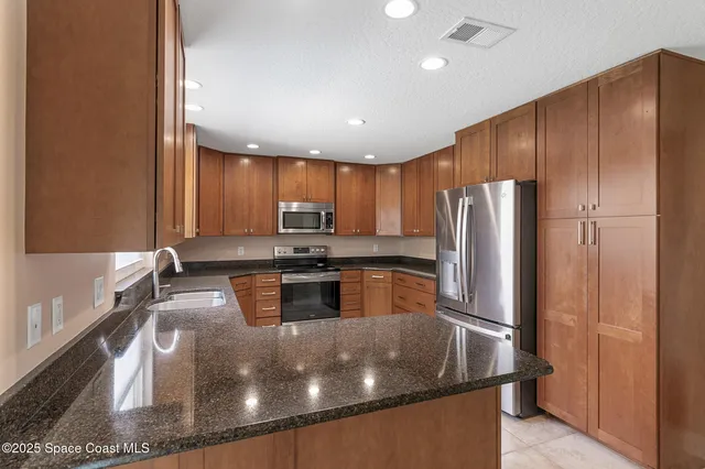 a kitchen with stainless steel appliances granite countertop a sink a stove and a refrigerator