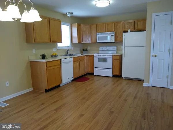 a kitchen with stainless steel appliances granite countertop a refrigerator a stove top oven a sink and dishwasher with wooden floor