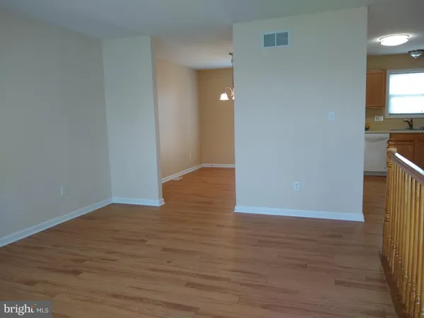 a view of an empty room with wooden floor and a fireplace