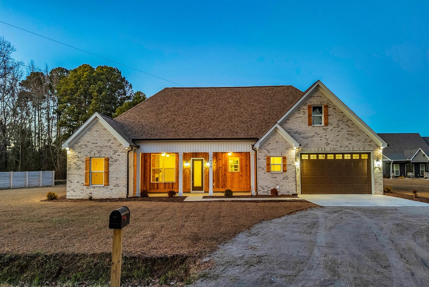 View of front of property with covered porch, driveway, brick siding, and a garage