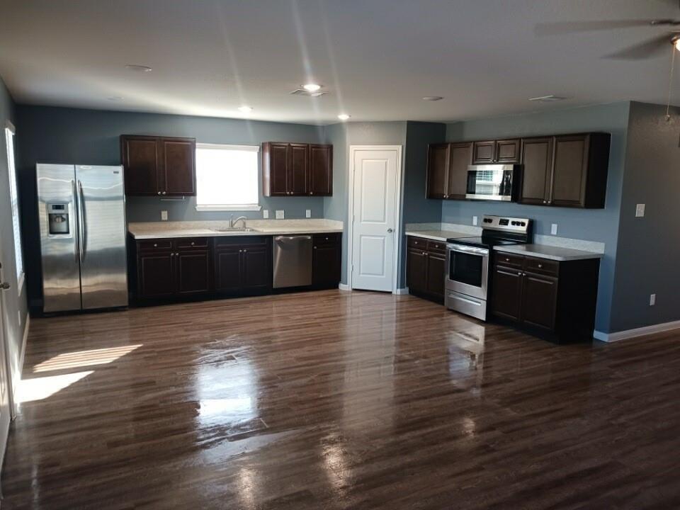 a large kitchen with stainless steel appliances wooden floors and wooden cabinets