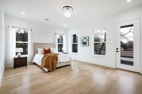 a spacious bedroom with a bed and dresser with wooden floor