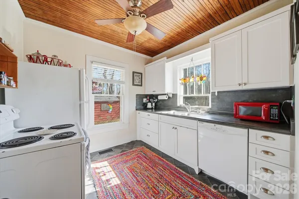 a kitchen with granite countertop a sink cabinets stainless steel appliances and a window