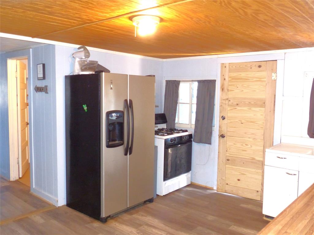 286 North Fm 1851 Voca, TX 76887 - Photo 13 of 23 Kitchen with stainless steel refrigerator with ice dispenser, wood finished floors, gas range, and wooden ceiling