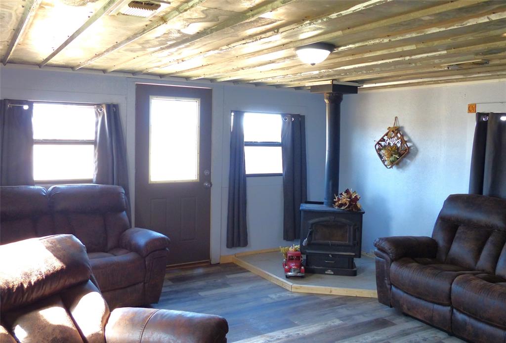 286 North Fm 1851 Voca, TX 76887 - Photo 17 of 23 Living area with visible vents, a wood stove, wood finished floors, and baseboards