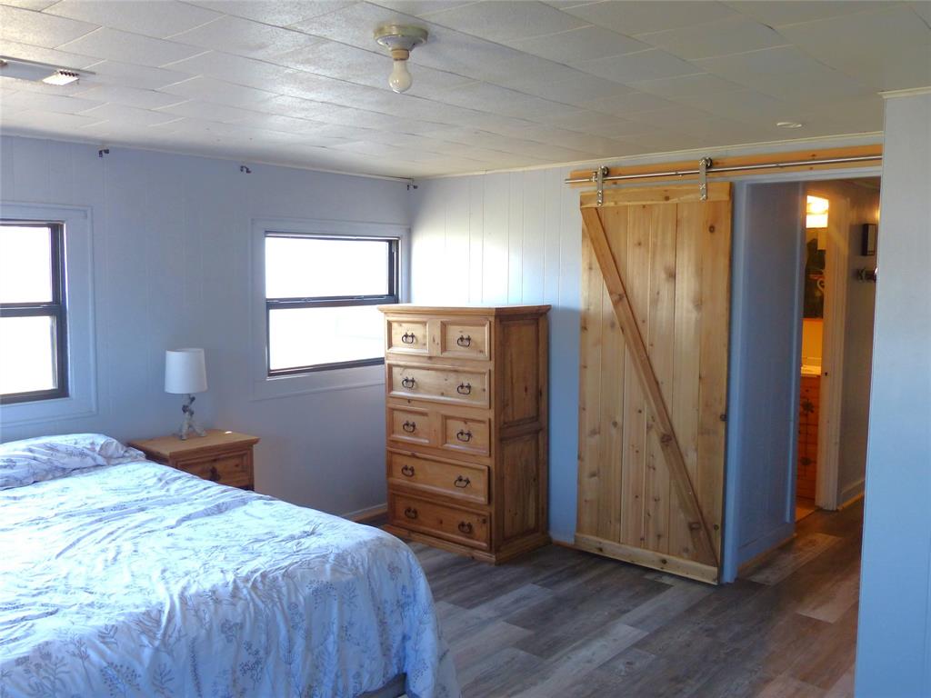 286 North Fm 1851 Voca, TX 76887 - Photo 9 of 23 Bedroom featuring ornamental molding, a barn door, and wood finished floors