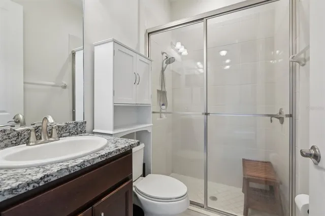 a bathroom with a granite countertop sink a toilet and shower