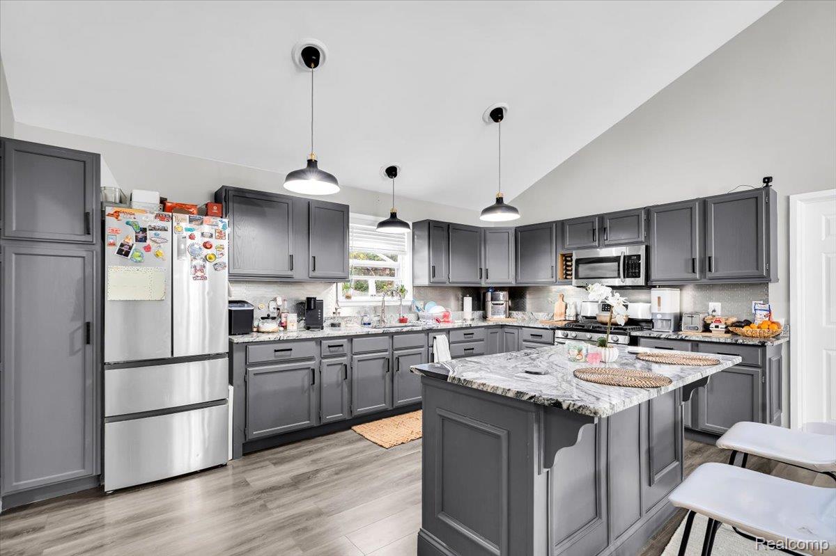 3260 Isabelle Street Inkster, MI 48141 - Photo 12 of 35 Kitchen featuring gray cabinetry, stainless steel appliances, a center island with a marbled countertop, and wood-finish flooring