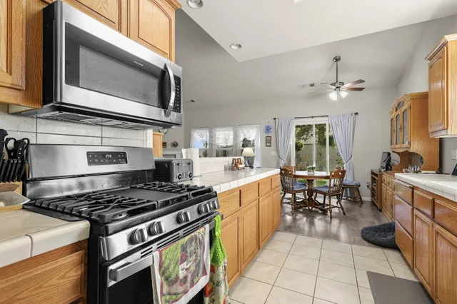 a kitchen with stainless steel appliances granite countertop a stove top oven a sink dishwasher a dining table and chairs with wooden floor