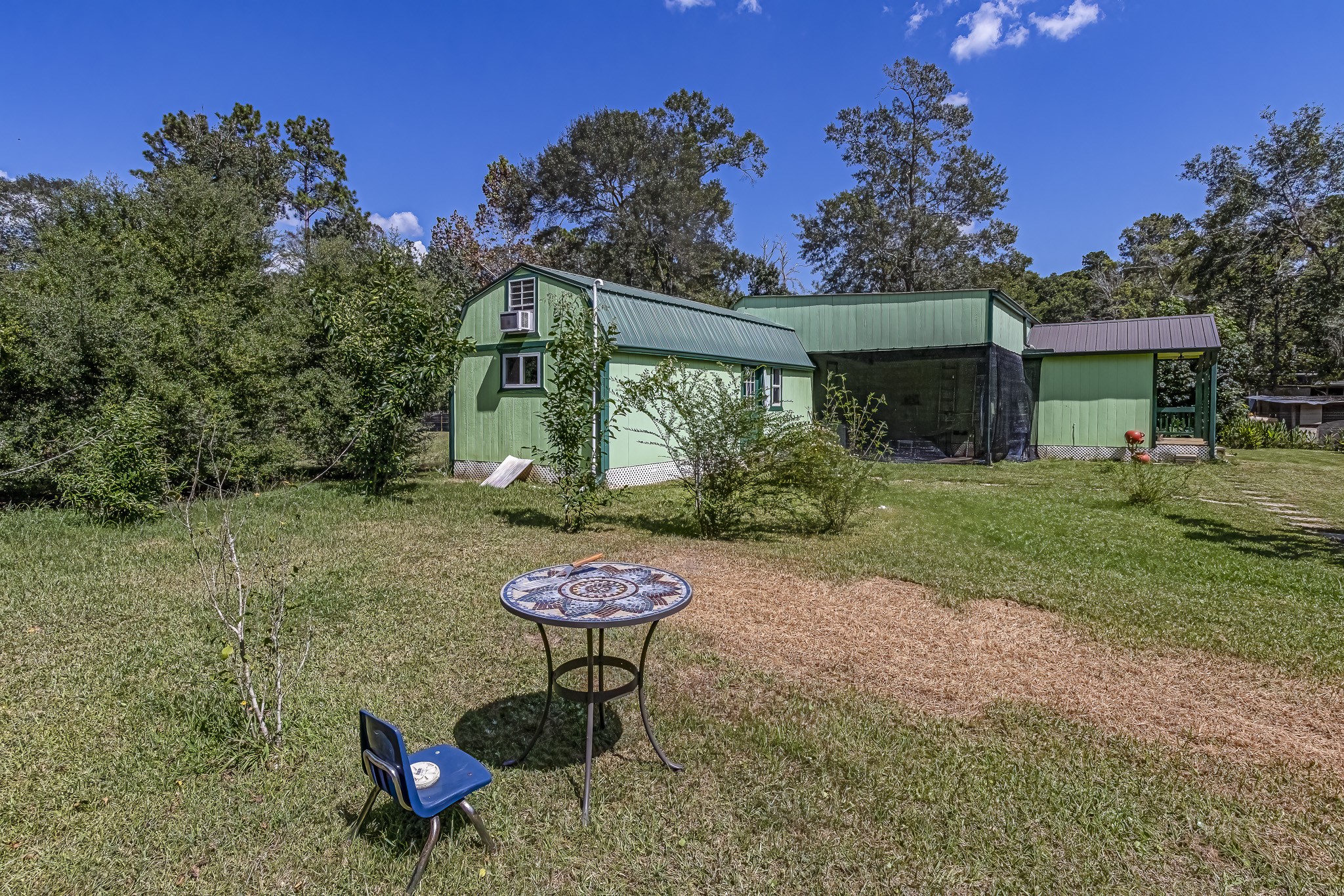 121 Tidwell Road Shepherd, TX 77371 - Photo 20 of 21 a view of a backyard with table and chairs potted plants and a palm tree