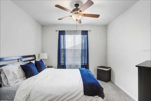 a bedroom with a bed ceiling fan and a window