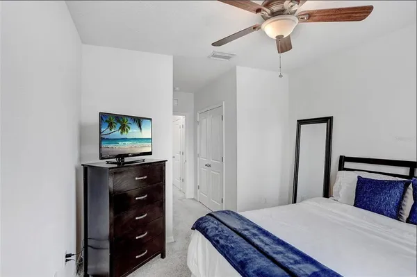 a bedroom with a bed and a flat tv screen on a dresser