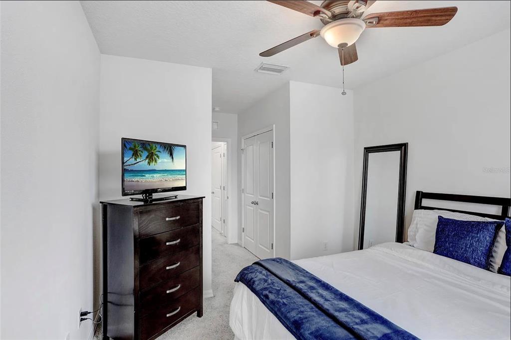 32934 Kaloko Road Wesley Chapel, FL 33543 - Photo 20 of 39 a bedroom with a bed and a flat tv screen on a dresser