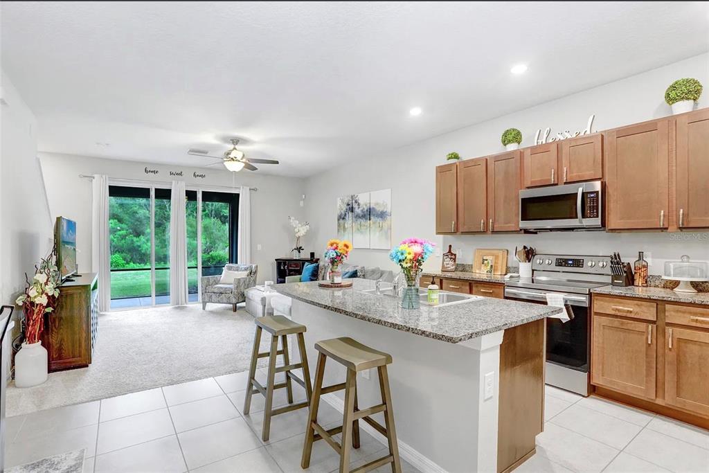 32934 Kaloko Road Wesley Chapel, FL 33543 - Photo 7 of 39 a kitchen with stainless steel appliances granite countertop a stove top oven a sink dishwasher a dining table and chairs with wooden floor