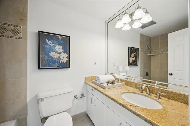 a bathroom with a granite countertop toilet a sink and a mirror