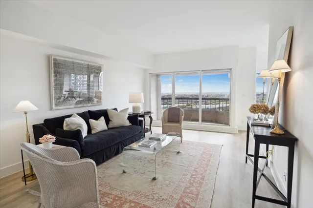 a living room with furniture a large window and wooden floor