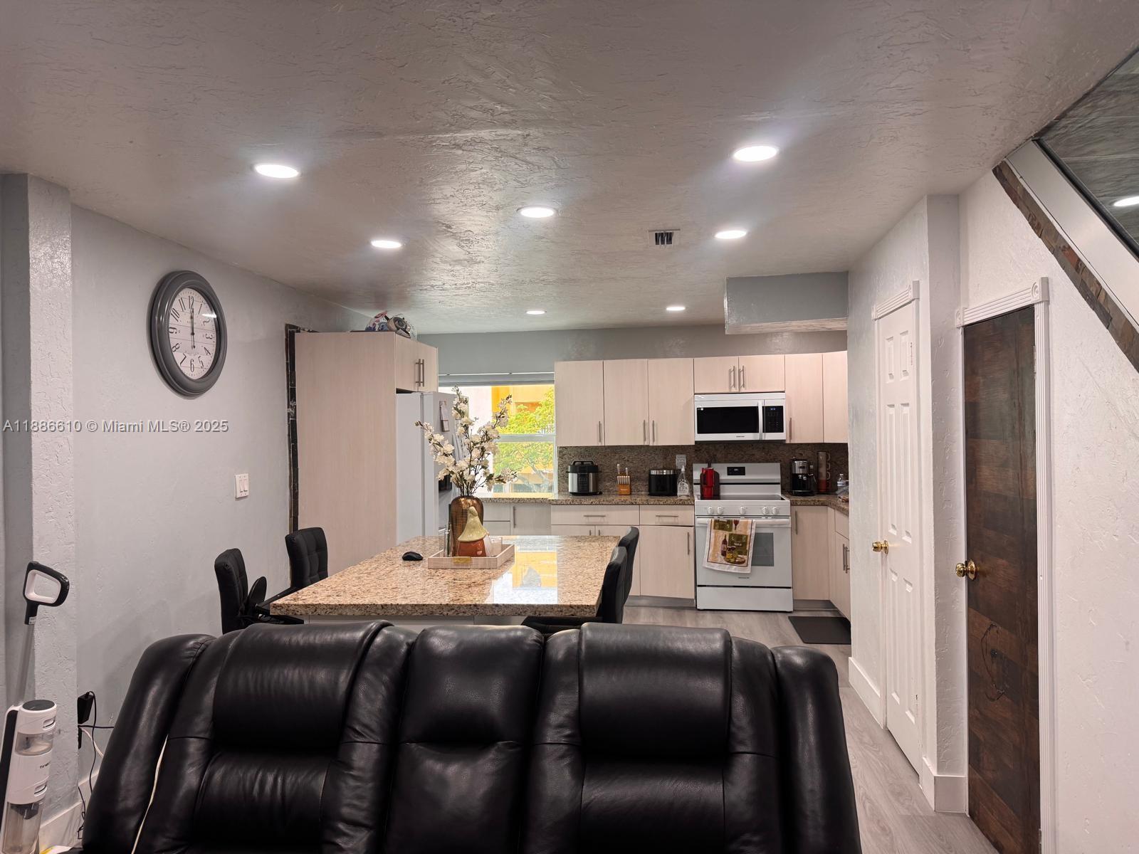 1560 West 46th Street, Unit 236 Hialeah, FL 33012 - Photo 2 of 19 a living room with stainless steel appliances furniture a clock and a view of kitchen