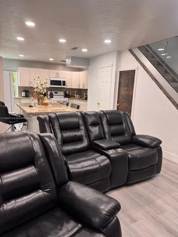 a living room with furniture and a glass table with kitchen view